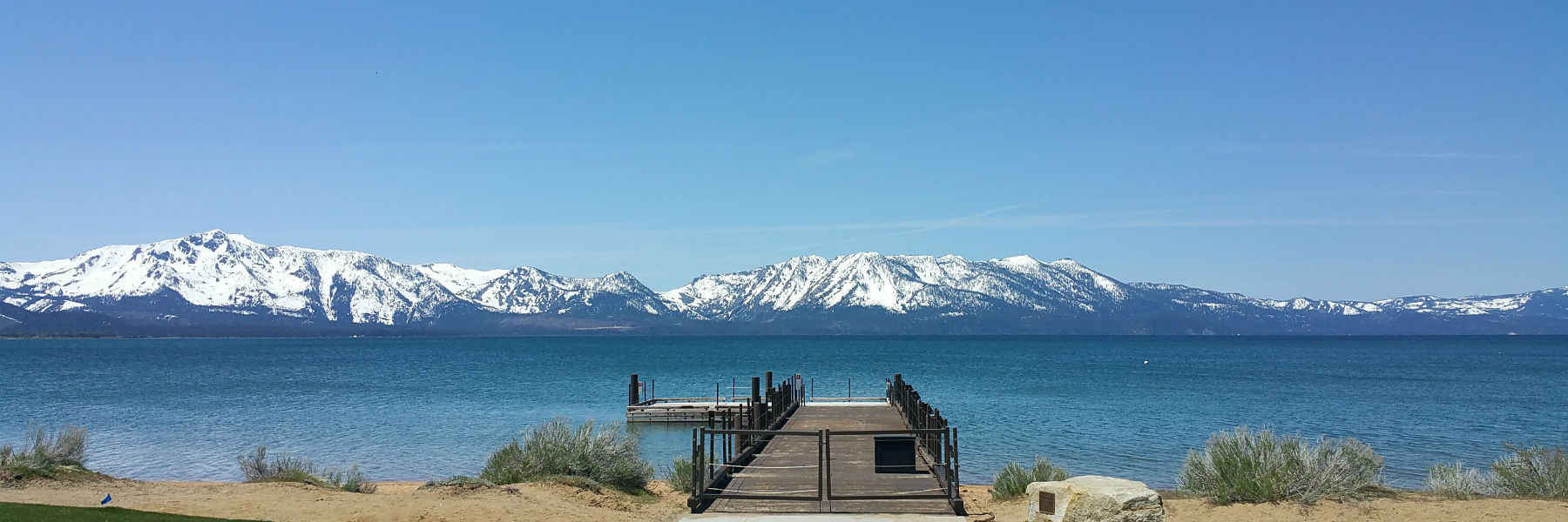 Dock in lake in front of snowy mountains